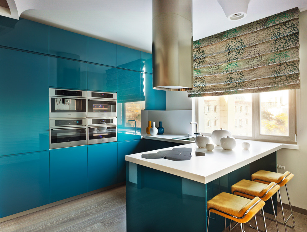 Idee per una cucina ad U contemporanea con ante lisce, ante blu, elettrodomestici in acciaio inossidabile, parquet chiaro e pavimento beige