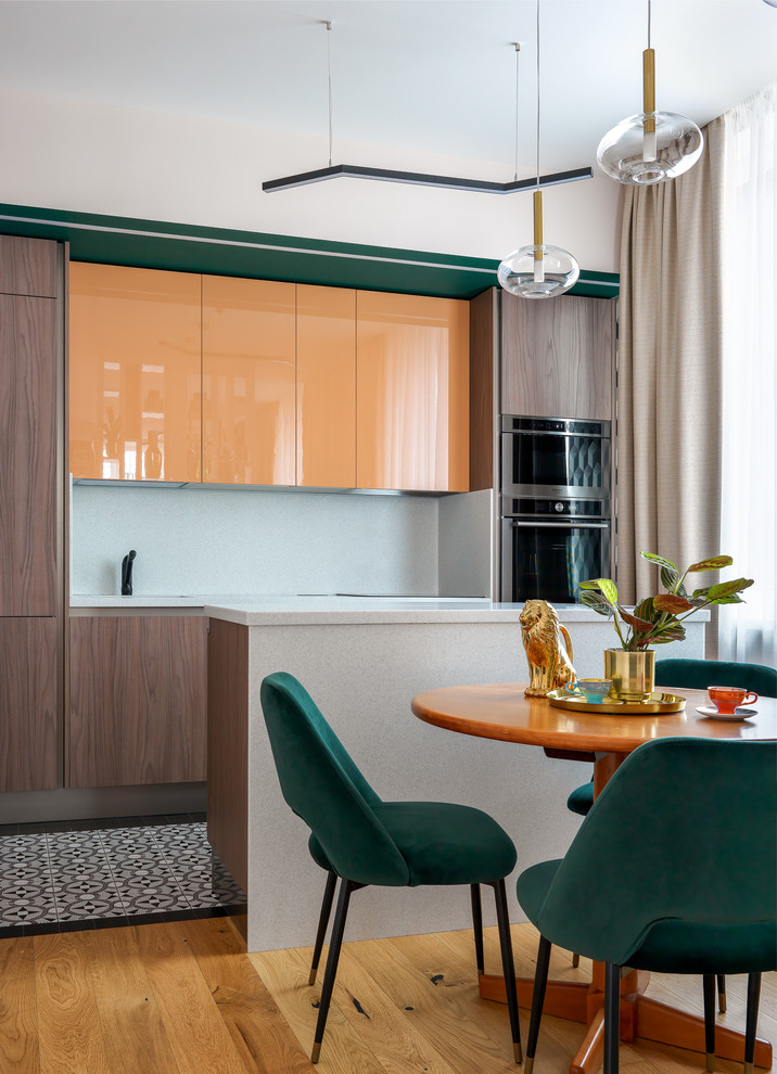 Einzeilige Moderne Wohnküche mit flächenbündigen Schrankfronten, orangefarbenen Schränken, Küchenrückwand in Weiß, Kücheninsel, buntem Boden, weißer Arbeitsplatte und Küchengeräten aus Edelstahl in Moskau