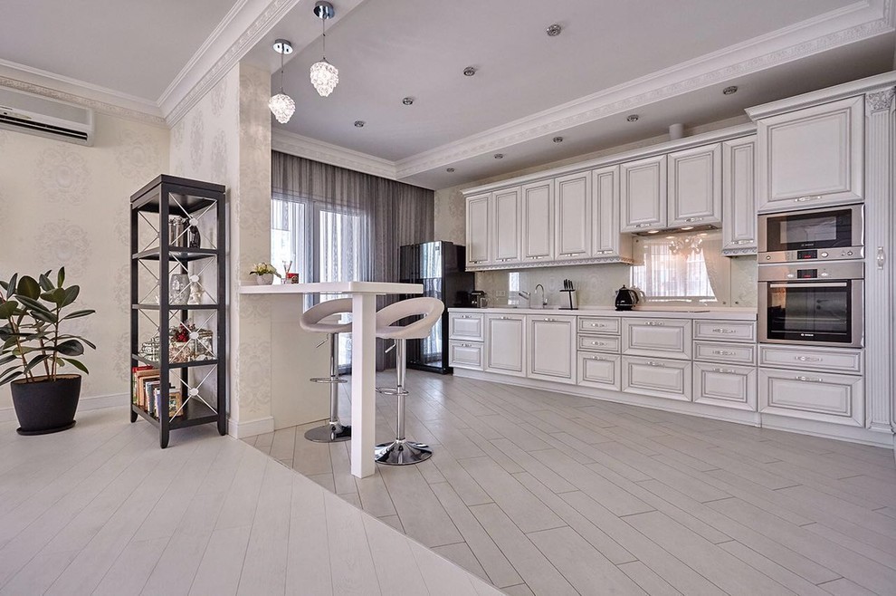 Elegant kitchen photo in Other with white cabinets, beige backsplash, stainless steel appliances and a peninsula