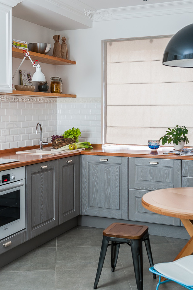 Inredning av ett skandinaviskt litet gul gult kök, med en nedsänkt diskho, luckor med upphöjd panel, grå skåp, träbänkskiva, vitt stänkskydd, stänkskydd i tunnelbanekakel, färgglada vitvaror, klinkergolv i keramik och grått golv
