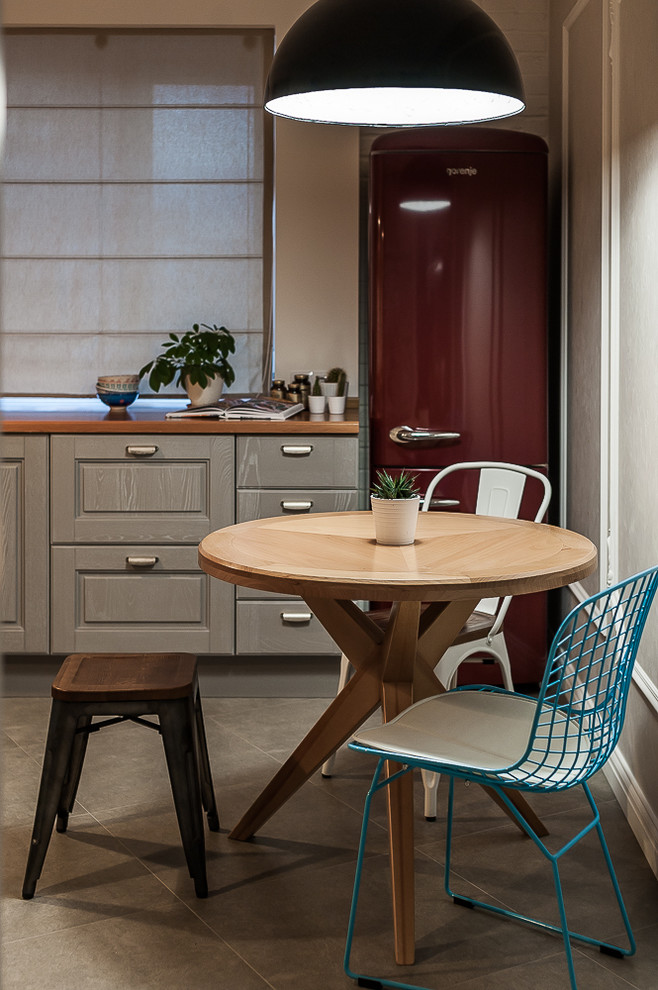 Small scandi grey and brown l-shaped kitchen/diner in Other with a submerged sink, raised-panel cabinets, grey cabinets, wood worktops, white splashback, metro tiled splashback, white appliances, ceramic flooring, grey floors and brown worktops.