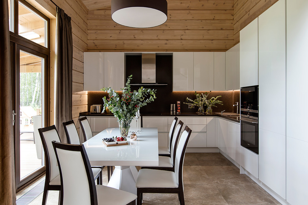 Пример оригинального дизайна: угловая кухня-гостиная в современном стиле с накладной мойкой, плоскими фасадами, белыми фасадами, черной техникой и серым полом без острова