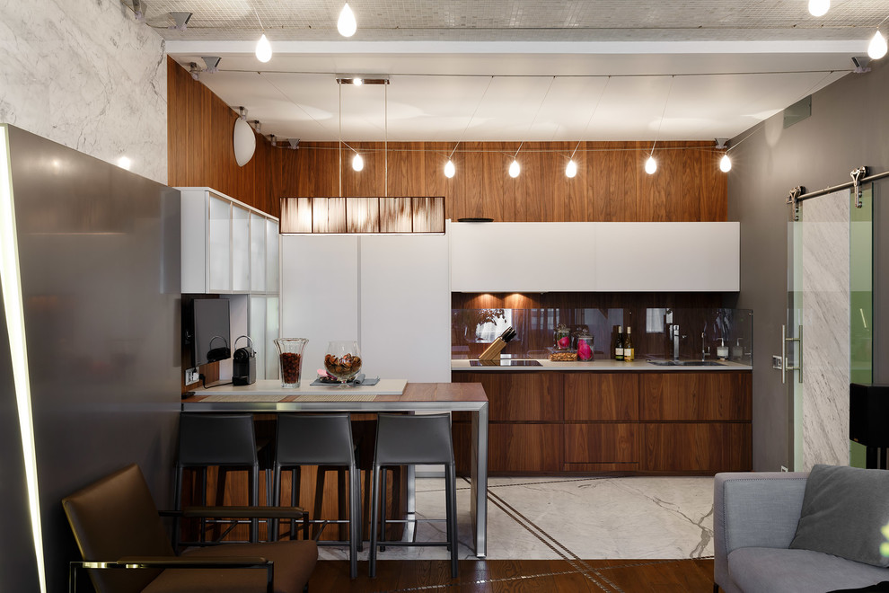 Foto på ett funkis kök med öppen planlösning, med en dubbel diskho, släta luckor, skåp i mellenmörkt trä, glaspanel som stänkskydd, integrerade vitvaror och en halv köksö