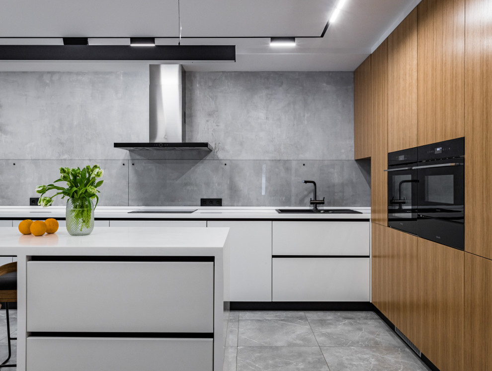 Foto på ett funkis vit kök, med en nedsänkt diskho, släta luckor, vita skåp, grått stänkskydd, glaspanel som stänkskydd, svarta vitvaror, en köksö och grått golv