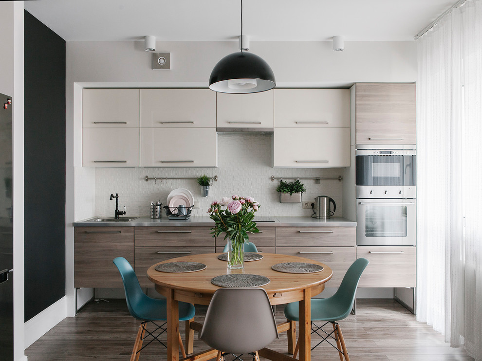 Modern inredning av ett grå linjärt grått kök och matrum, med en nedsänkt diskho, släta luckor, grå skåp, rostfria vitvaror och grått golv