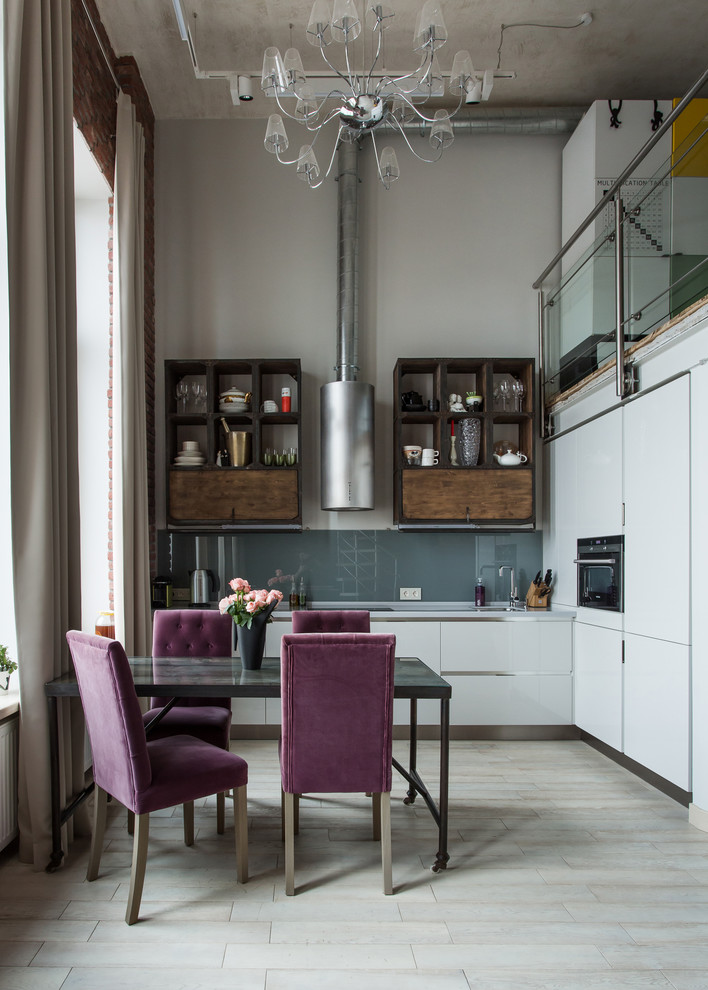 Свежая идея для дизайна: угловая кухня в стиле лофт с обеденным столом, плоскими фасадами, белыми фасадами и серым фартуком - отличное фото интерьера
