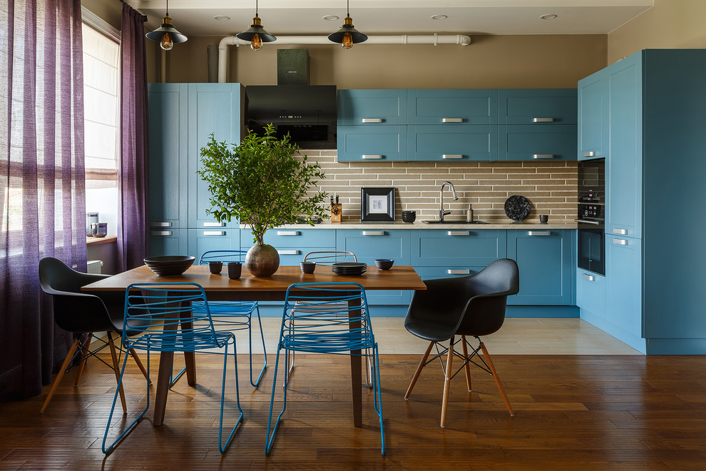 Photo of an industrial kitchen/diner in Other with a built-in sink, shaker cabinets, turquoise cabinets, beige splashback, black appliances, beige floors and beige worktops.