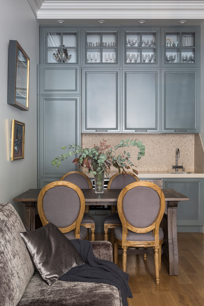 Klassisk inredning av ett linjärt kök med öppen planlösning, med en undermonterad diskho, grå skåp, beige stänkskydd, stänkskydd i mosaik, rostfria vitvaror, mellanmörkt trägolv och brunt golv