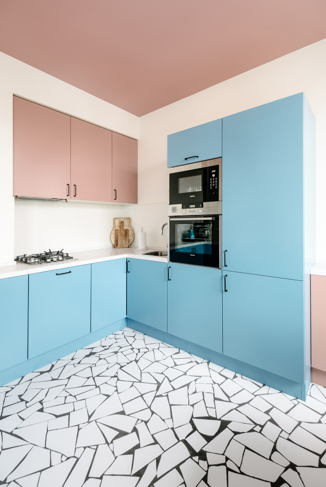 Пример оригинального дизайна: кухня в стиле модернизм с врезной мойкой, плоскими фасадами, синими фасадами, белым фартуком, техникой из нержавеющей стали, разноцветным полом и белой столешницей