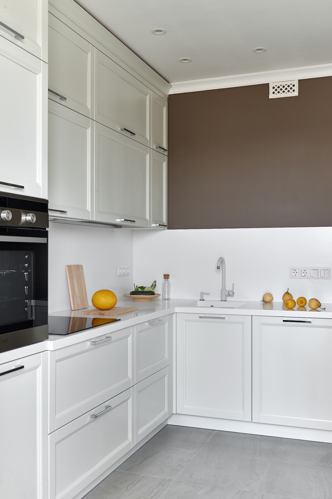 Стильный дизайн: угловая кухня в современном стиле с фасадами в стиле шейкер, белыми фасадами, серым полом и белой столешницей - последний тренд