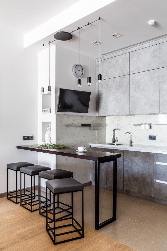 На фото: прямая кухня в современном стиле с плоскими фасадами, серыми фасадами, бежевым полом, полуостровом и телевизором