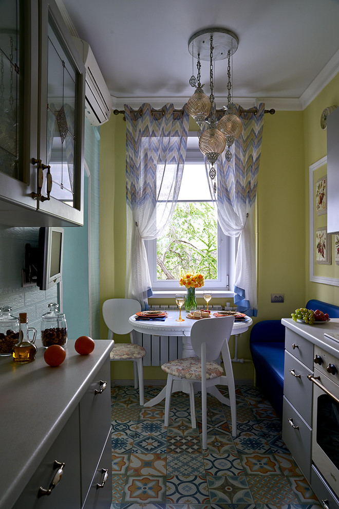 Cette photo montre une cuisine parallèle tendance fermée avec un placard à porte plane, des portes de placard grises, un électroménager blanc, aucun îlot et un sol multicolore.