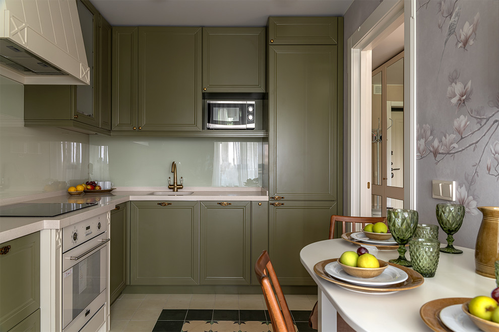 Bild på ett mellanstort vintage vit vitt kök, med en integrerad diskho, luckor med infälld panel, gröna skåp, bänkskiva i koppar, glaspanel som stänkskydd, vita vitvaror, cementgolv och grönt golv