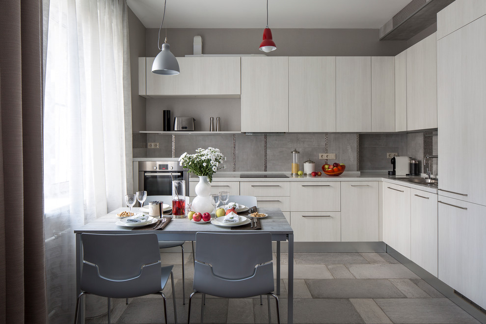 Offene Moderne Küche in grau-weiß ohne Insel in L-Form mit flächenbündigen Schrankfronten, hellen Holzschränken, Küchenrückwand in Grau, Küchengeräten aus Edelstahl und Einbauwaschbecken in Moskau