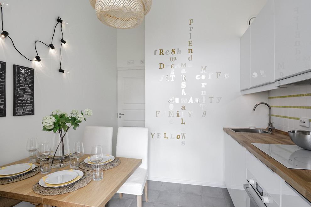 Exempel på ett avskilt, mellanstort skandinaviskt linjärt kök, med en nedsänkt diskho, släta luckor, vita skåp, träbänkskiva, stänkskydd i keramik, vita vitvaror, klinkergolv i porslin och grått golv