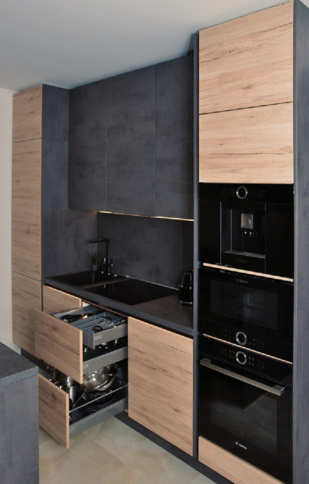 Inspiration for a small contemporary galley open plan kitchen in Other with a submerged sink, flat-panel cabinets, light wood cabinets, laminate countertops, black splashback, an island and black worktops.