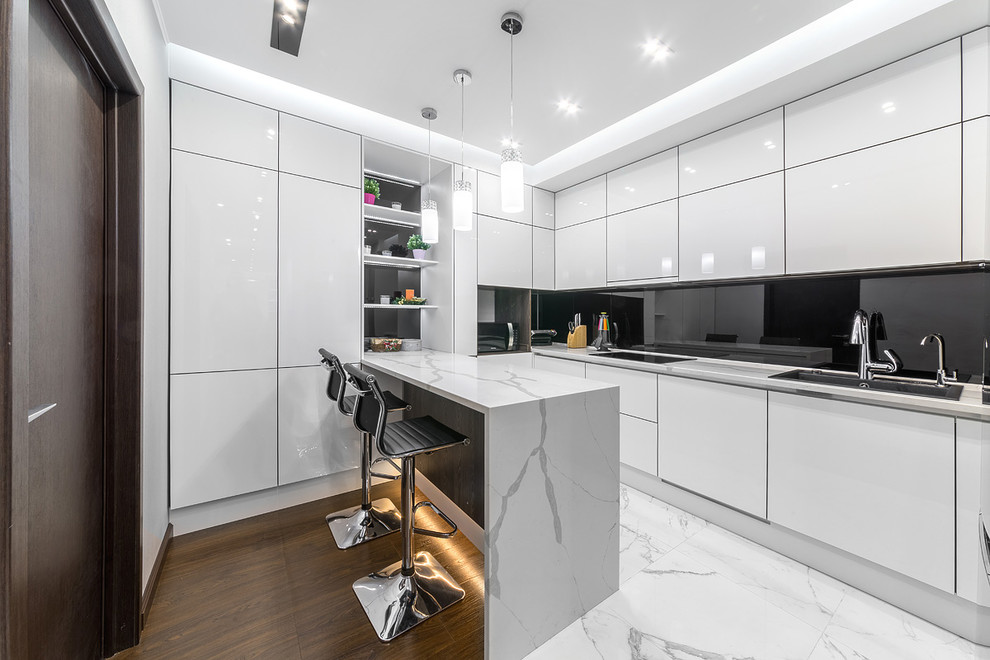 Foto på ett avskilt, mellanstort funkis kök, med släta luckor, vita skåp, svart stänkskydd, glaspanel som stänkskydd, en halv köksö, vitt golv och en nedsänkt diskho