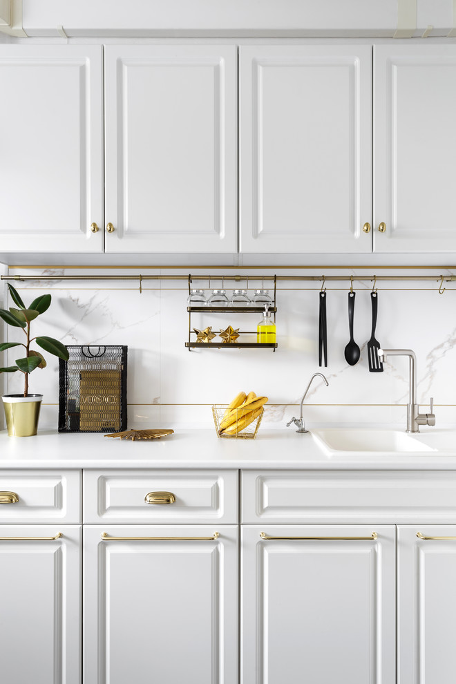 Klassische Küche mit Einbauwaschbecken, profilierten Schrankfronten, weißen Schränken, Küchenrückwand in Weiß und weißer Arbeitsplatte in Sonstige