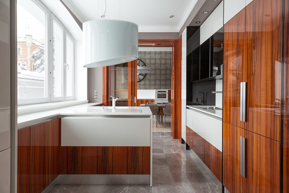 Inspiration for a contemporary l-shaped enclosed kitchen in London with a submerged sink, flat-panel cabinets, brown cabinets, white splashback, integrated appliances, a breakfast bar, grey floors and white worktops.