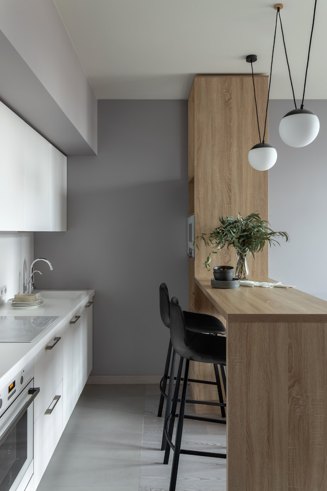 На фото: кухня-гостиная среднего размера в скандинавском стиле с белыми фасадами, островом и серым полом с