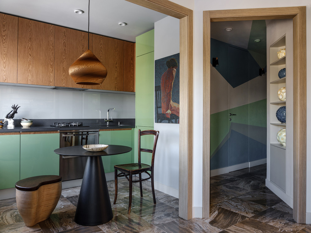 Esempio di una cucina abitabile contemporanea con ante lisce, ante verdi, elettrodomestici in acciaio inossidabile, pavimento marrone, top nero, lavello sottopiano, paraspruzzi grigio e paraspruzzi con lastra di vetro