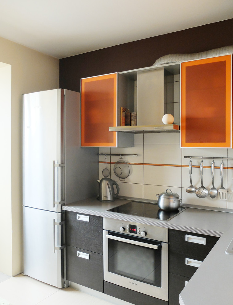 Photo of a small contemporary l-shaped kitchen/diner in Moscow with flat-panel cabinets, orange cabinets, laminate countertops, white splashback, ceramic splashback, stainless steel appliances, ceramic flooring and no island.