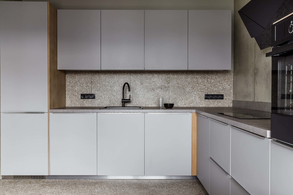Foto på ett funkis grå l-kök, med släta luckor, grå skåp, grått stänkskydd, terrazzogolv och grått golv