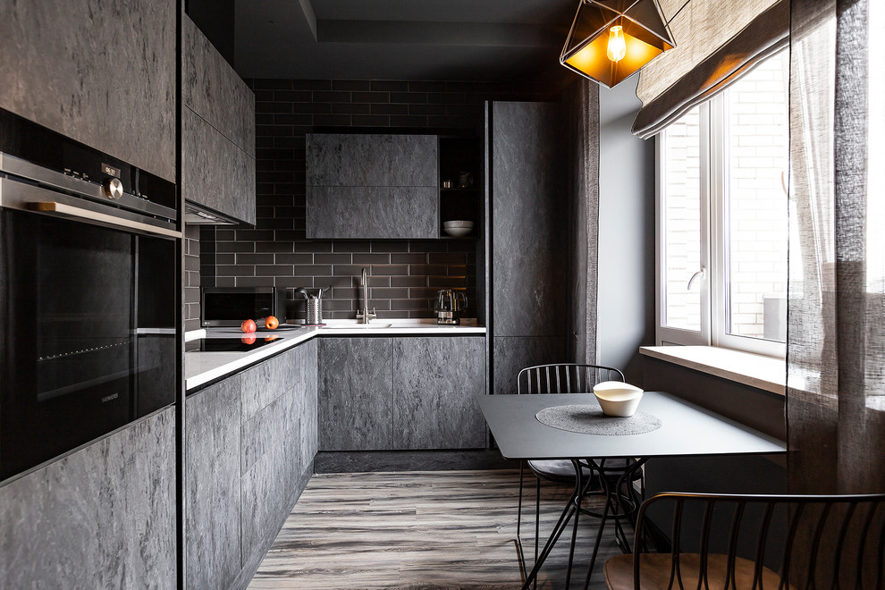 Immagine di una cucina contemporanea con lavello integrato, ante lisce, ante grigie, paraspruzzi grigio, elettrodomestici in acciaio inossidabile, pavimento in legno massello medio, pavimento marrone e top bianco