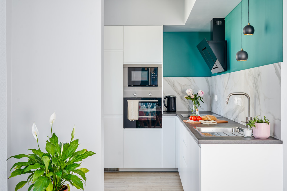 Scandi l-shaped kitchen in Saint Petersburg with a built-in sink, flat-panel cabinets, white cabinets, white splashback, stainless steel appliances, no island, beige floors and grey worktops.