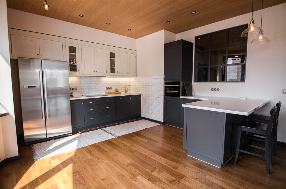 Klassisk inredning av ett mellanstort vit vitt kök, med en integrerad diskho, skåp i shakerstil, svarta skåp, bänkskiva i koppar, vitt stänkskydd, stänkskydd i tunnelbanekakel, rostfria vitvaror, mörkt trägolv, en halv köksö och brunt golv