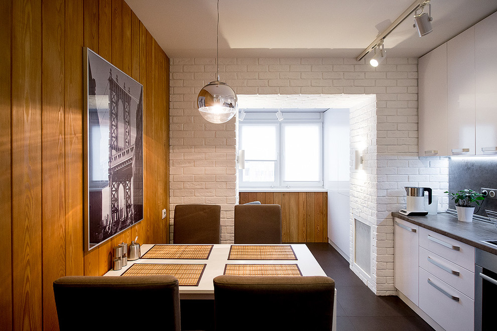 Стильный дизайн: прямая кухня среднего размера в современном стиле с обеденным столом, плоскими фасадами, белыми фасадами и серым фартуком - последний тренд