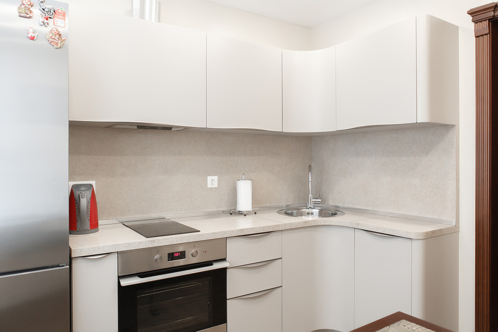 Small contemporary l-shaped kitchen in Moscow with a submerged sink, beige cabinets, granite worktops, beige splashback, ceramic splashback, stainless steel appliances, laminate floors, an island, brown floors and beige worktops.