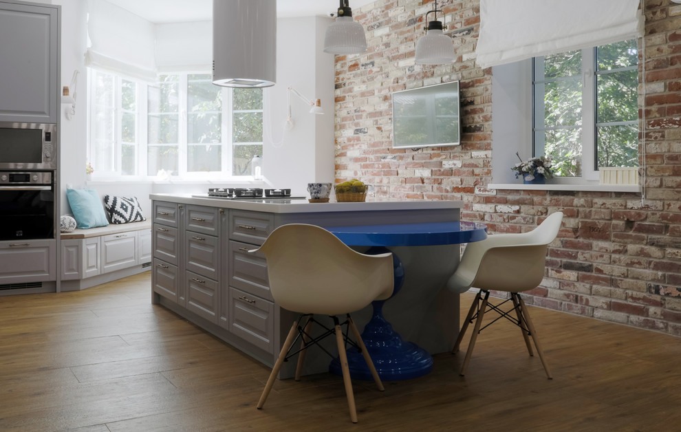 На фото: кухня в стиле лофт с обеденным столом, фасадами с выступающей филенкой, серыми фасадами и белой столешницей
