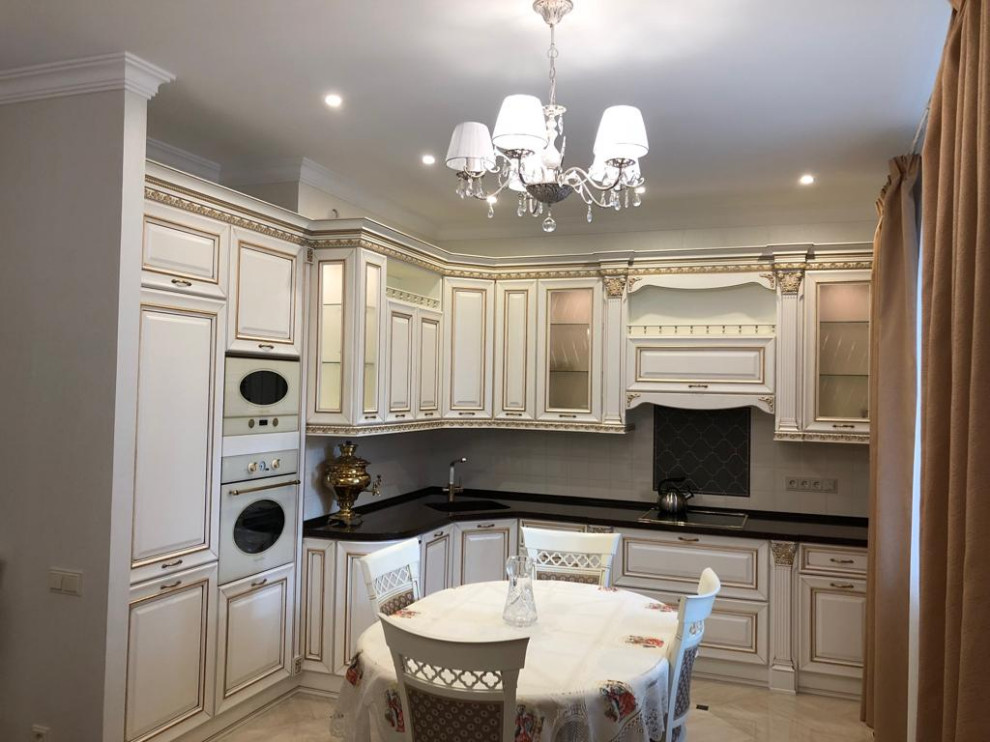 Design ideas for a medium sized classic l-shaped open plan kitchen in Moscow with a single-bowl sink, beaded cabinets, beige cabinets, engineered stone countertops, beige splashback, ceramic splashback, white appliances, porcelain flooring, no island, beige floors and black worktops.