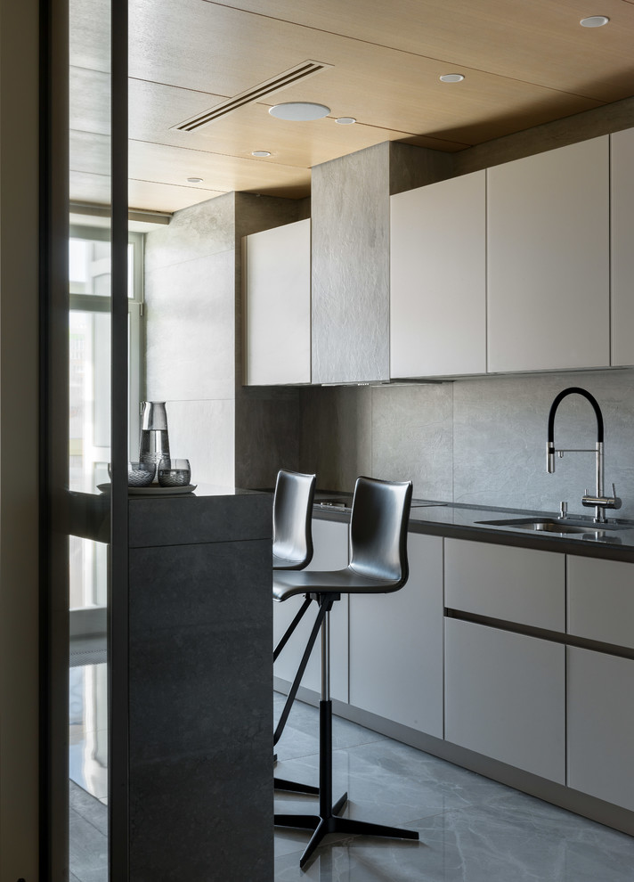 Idéer för stora skandinaviska linjära svart kök med öppen planlösning, med en undermonterad diskho, släta luckor, grå skåp, grått stänkskydd och grått golv