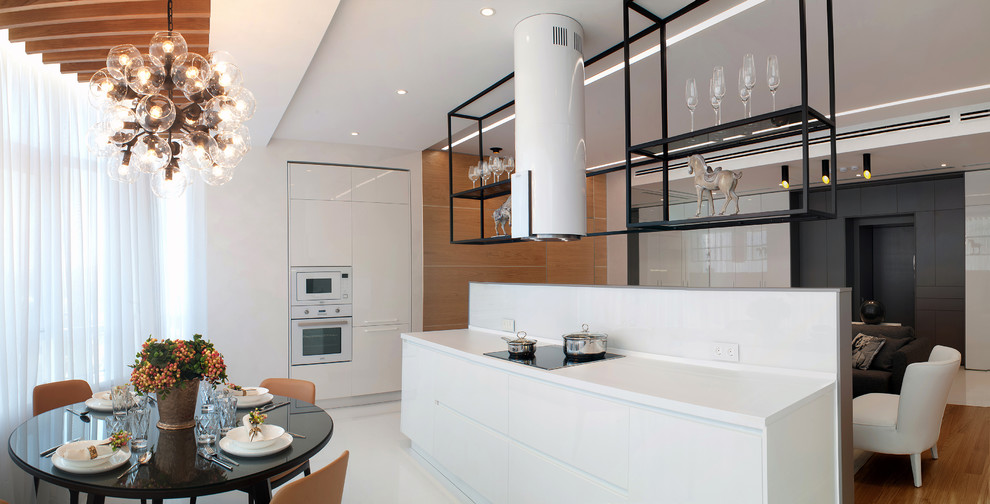 Ejemplo de cocina actual abierta con armarios con paneles lisos, puertas de armario blancas y electrodomésticos blancos