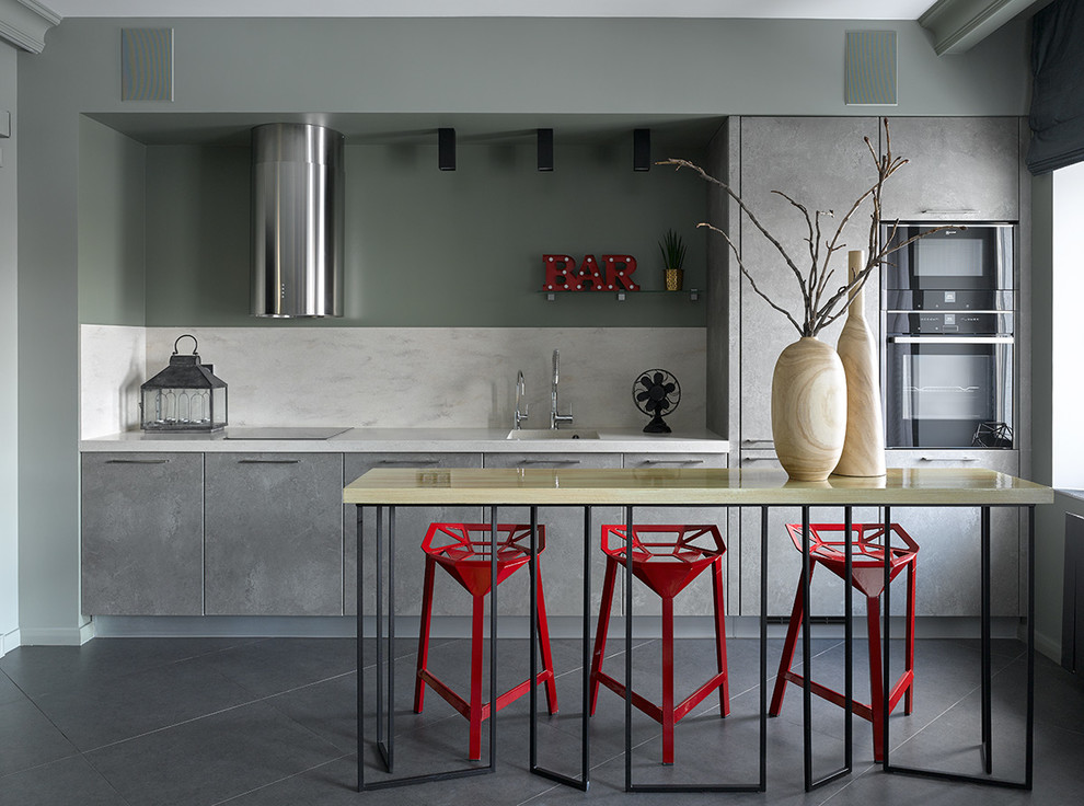 This is an example of a contemporary single-wall open plan kitchen in Moscow with an integrated sink, flat-panel cabinets, grey cabinets, white splashback, black appliances, no island and grey floors.