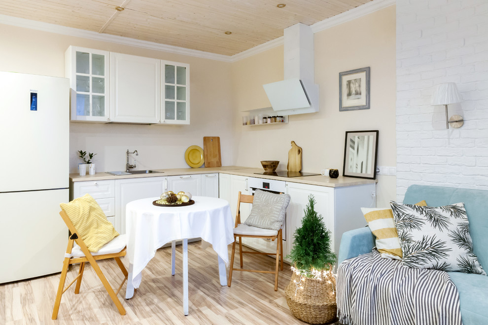 Foto på ett litet minimalistiskt beige kök, med en nedsänkt diskho, luckor med upphöjd panel, vita skåp, vita vitvaror, beiget golv och laminatgolv