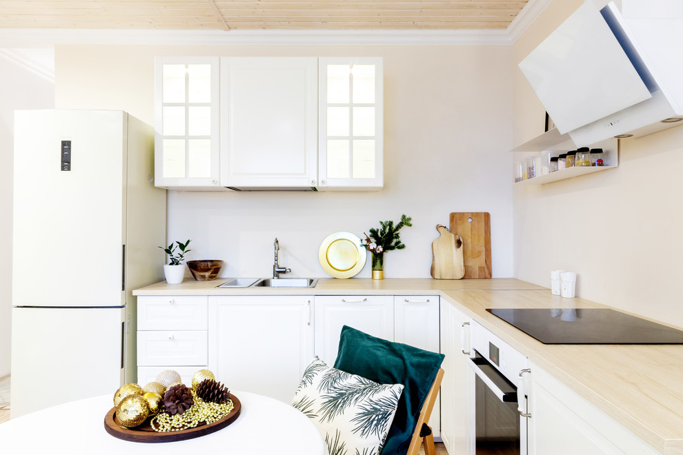 Bild på ett litet skandinaviskt beige beige kök, med en dubbel diskho, luckor med upphöjd panel, vita skåp, laminatbänkskiva, beige stänkskydd, vita vitvaror, laminatgolv och brunt golv