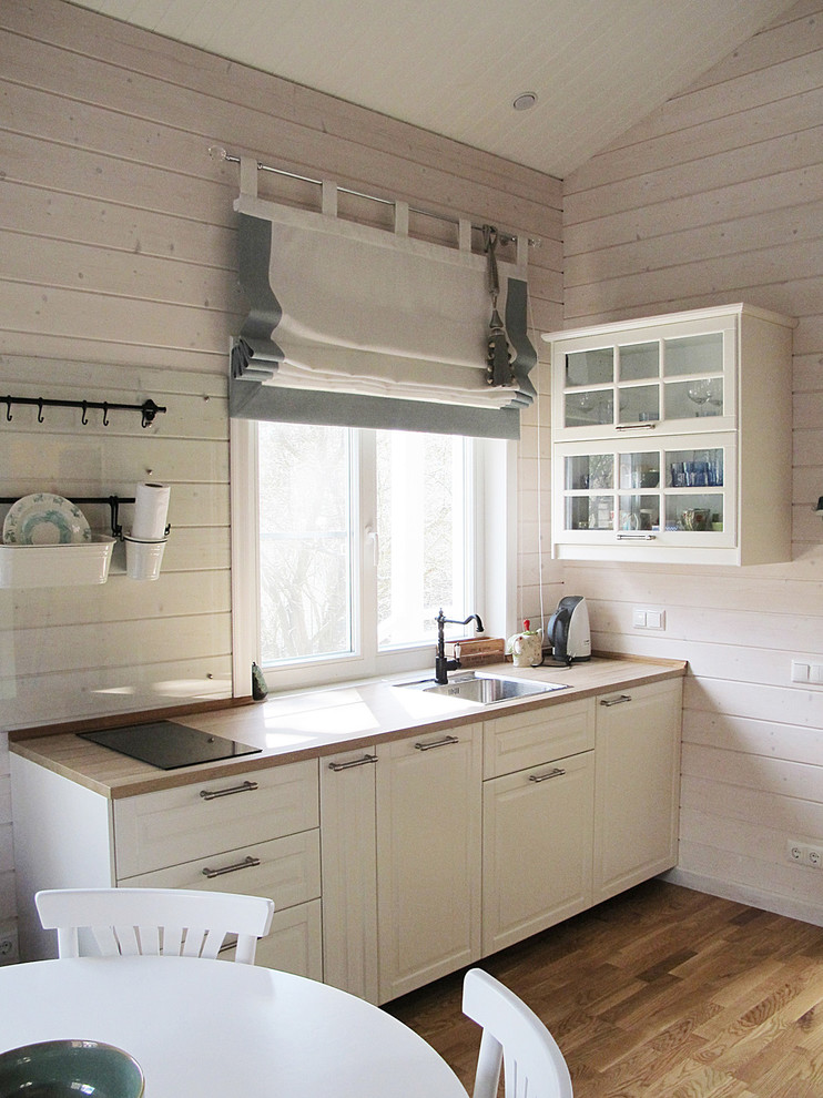 Inspiration pour une petite cuisine américaine linéaire rustique avec un évier posé, un placard avec porte à panneau surélevé, des portes de placard blanches, un plan de travail en bois et un sol en bois brun.