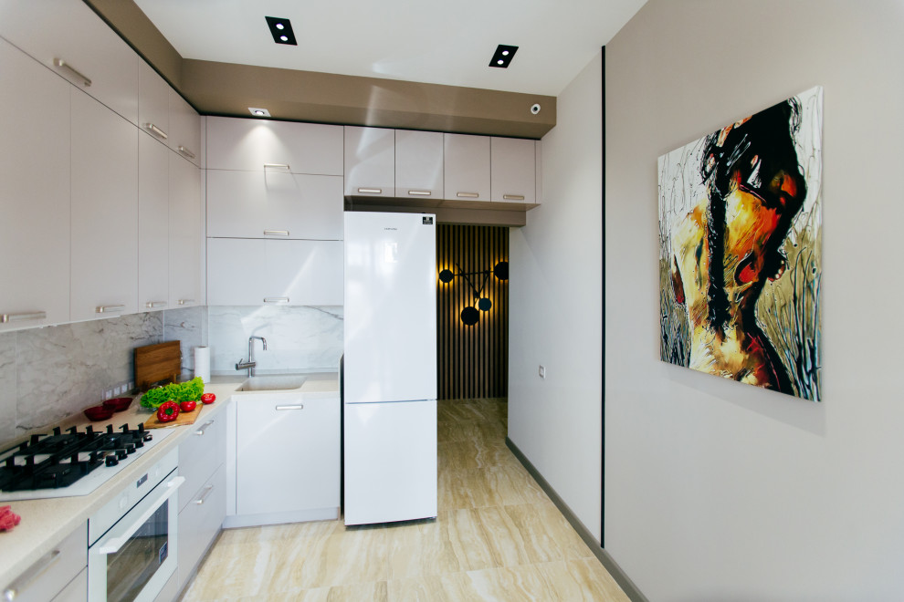 Immagine di una cucina a L contemporanea chiusa con ante lisce, ante grigie, paraspruzzi beige, elettrodomestici bianchi, nessuna isola, pavimento beige e top beige