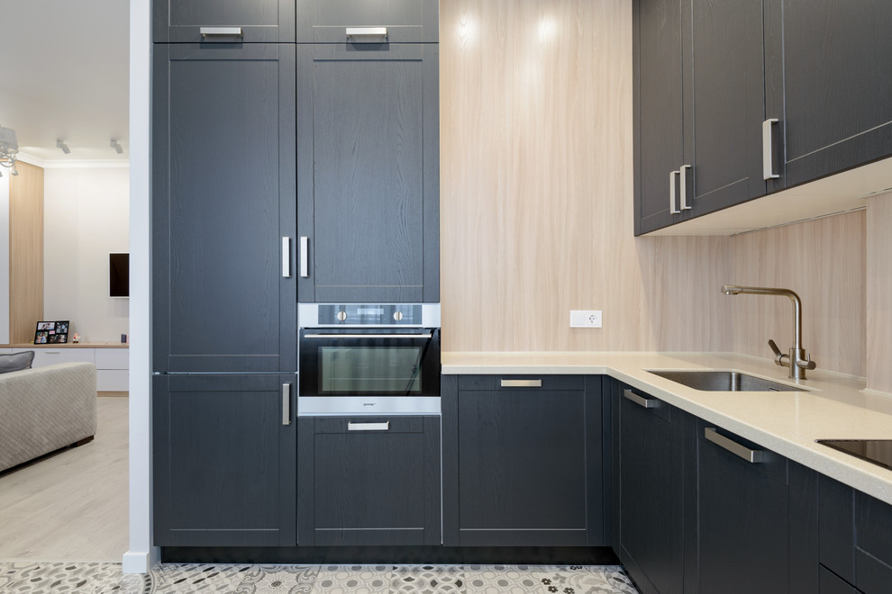 Inspiration for a small traditional l-shaped open plan kitchen in Novosibirsk with a single-bowl sink, raised-panel cabinets, grey cabinets, composite countertops, beige splashback, wood splashback, stainless steel appliances, ceramic flooring, no island, grey floors and beige worktops.