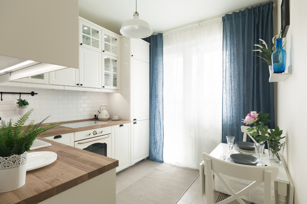 Exempel på ett mellanstort minimalistiskt kök, med en nedsänkt diskho, luckor med infälld panel, vita skåp, träbänkskiva, vitt stänkskydd, stänkskydd i keramik, vita vitvaror, klinkergolv i porslin och beiget golv