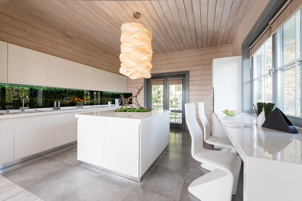Modern inredning av ett kök, med släta luckor, vita skåp, stänkskydd med metallisk yta och en köksö