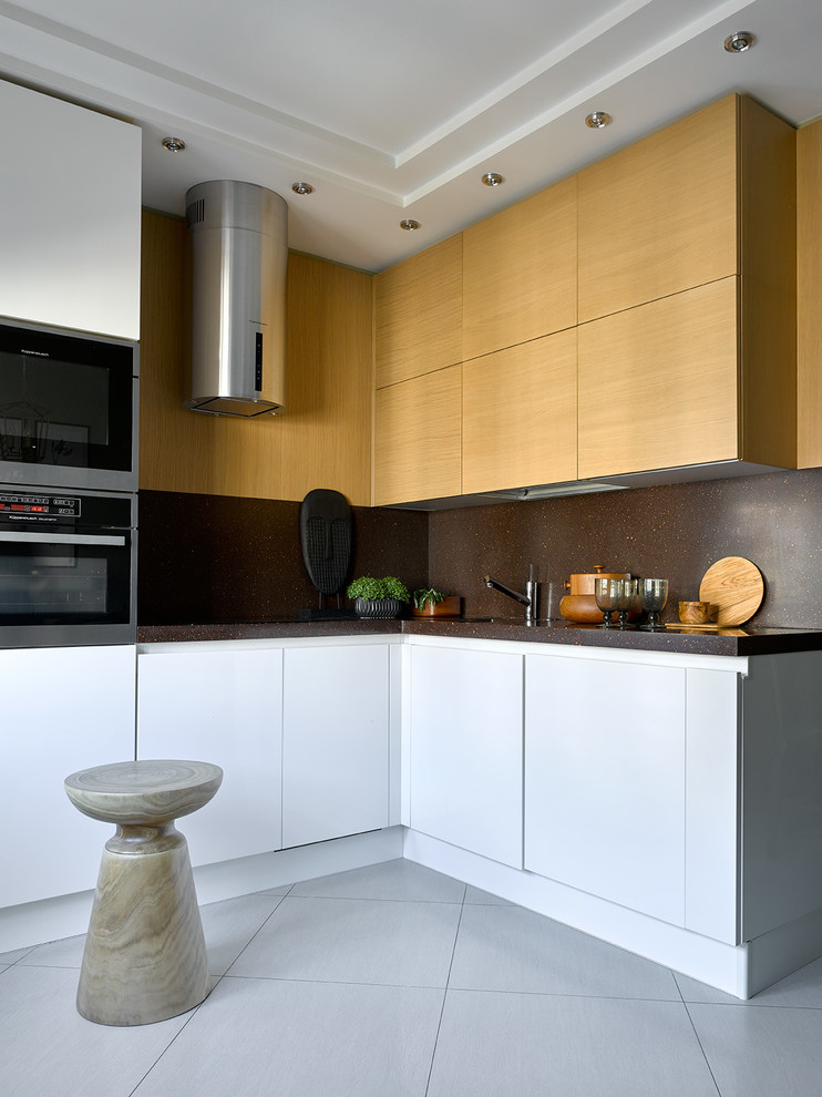 Bild på ett funkis kök, med släta luckor, brunt stänkskydd, rostfria vitvaror, vitt golv, en undermonterad diskho och skåp i mellenmörkt trä