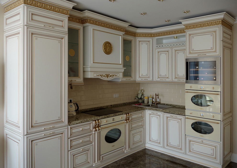 Пример оригинального дизайна: угловая кухня со стиральной машиной в классическом стиле с накладной мойкой, фасадами с выступающей филенкой, белыми фасадами, бежевым фартуком, фартуком из плитки кабанчик и белой техникой