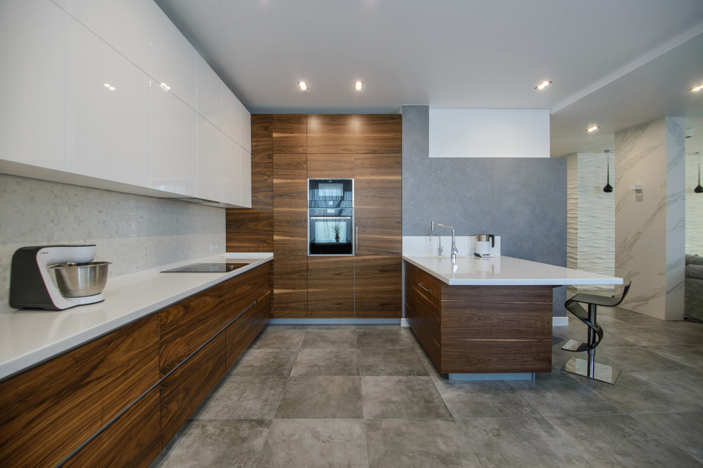 Inspiration for a large contemporary l-shaped kitchen in Novosibirsk with a submerged sink, flat-panel cabinets, medium wood cabinets, grey splashback, integrated appliances, a breakfast bar, grey floors and white worktops.