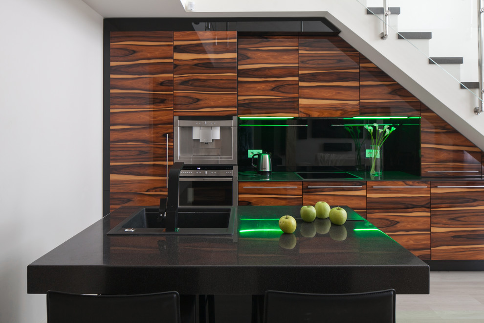 Diseño de cocina contemporánea con fregadero bajoencimera, puertas de armario de madera oscura, encimera de acrílico, electrodomésticos negros, suelo de madera clara y una isla