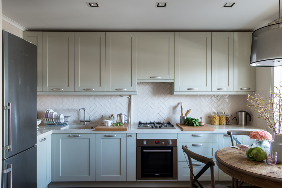 Foto di una cucina a L design chiusa con lavello integrato, ante in stile shaker, ante grigie, paraspruzzi bianco, elettrodomestici in acciaio inossidabile e top bianco