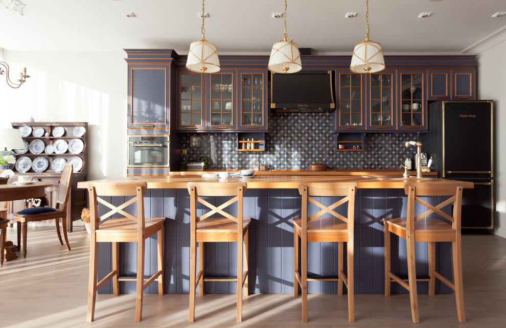 Свежая идея для дизайна: параллельная кухня-гостиная в классическом стиле с деревянной столешницей, синим фартуком, черной техникой, светлым паркетным полом, островом, стеклянными фасадами, синими фасадами, фартуком из керамогранитной плитки и бежевым полом - отличное фото интерьера